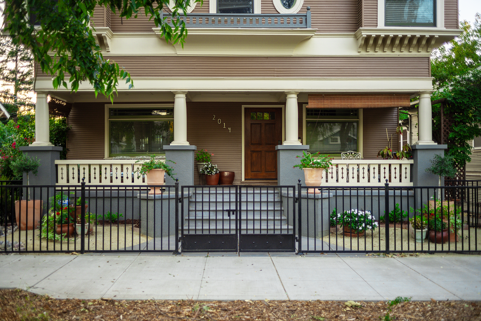 Elegant residential black ornamental metal fence enhancing home security and curb appeal, with a matching gateway leading to a classic brownstone house.